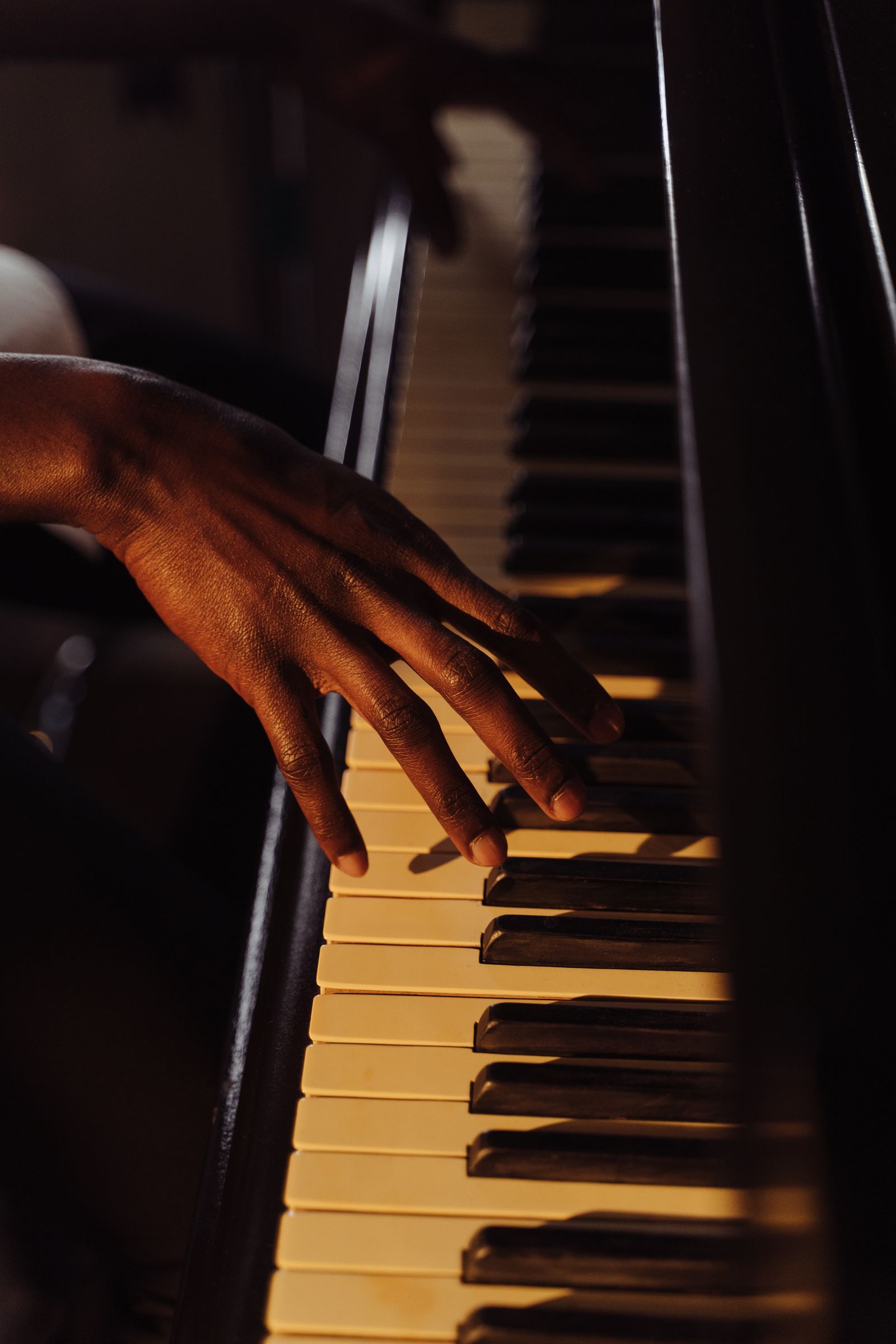 Hand on piano keys in warm light